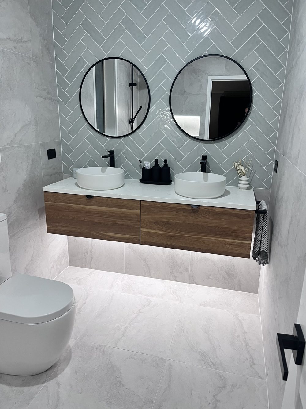 Bathroom with floating vanity, LED strip lighting under the cabinet and black fittings